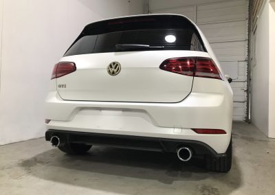 Back of the small sized Volkswagen in Satin Pearl White Color parked in car shop